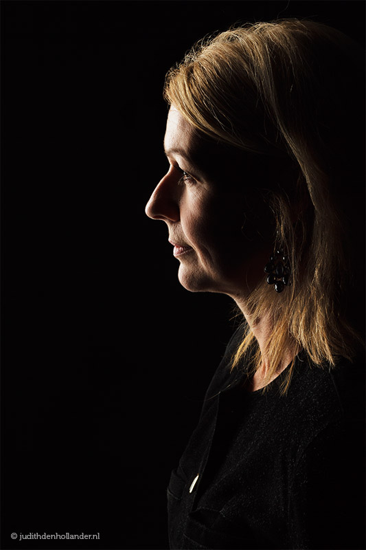 Low key portret, zwart op zwart, vrouw en profil | Portretfotografie Judith den Hollander.